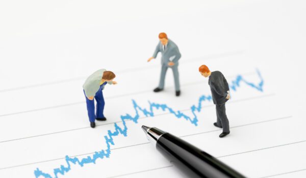 Miniature businesspeople examine a line chart.