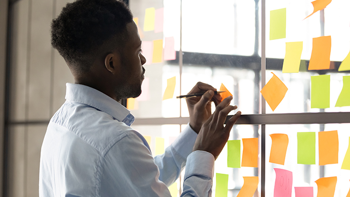 Young man writes on sticky notes, planning digital PR campaign